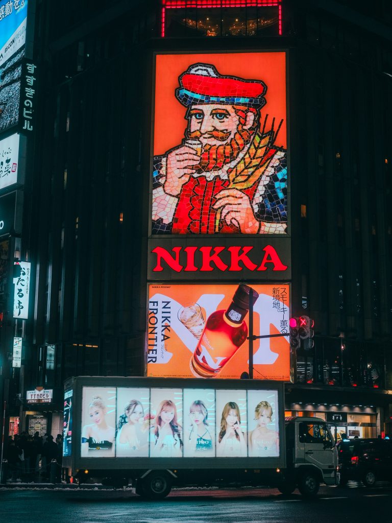 A large neon sign advertising Nikka whisky in a Japanese city.