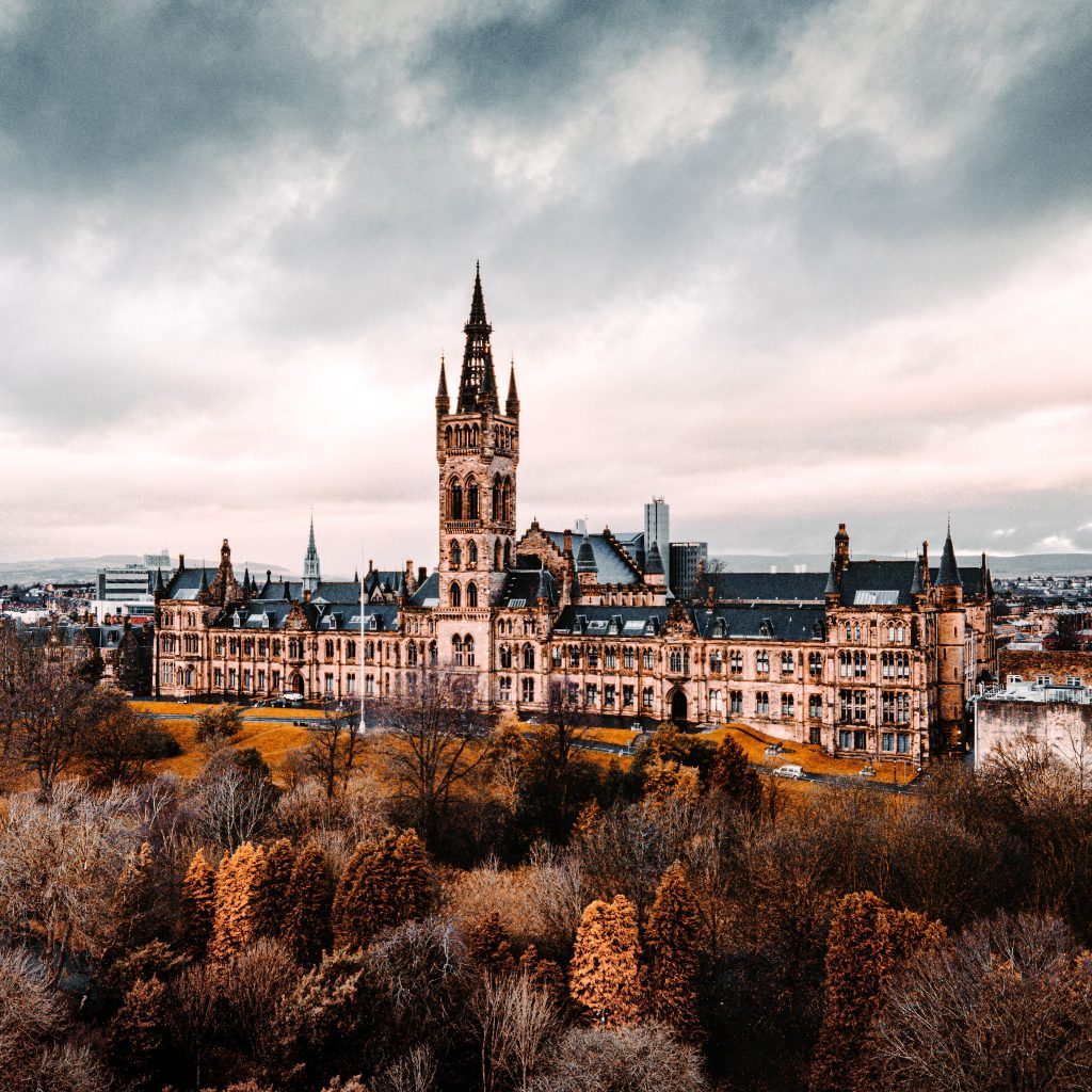 Stunning aerial shot of the University of Glasgow with autumn foliage, showcasing historic architecture.